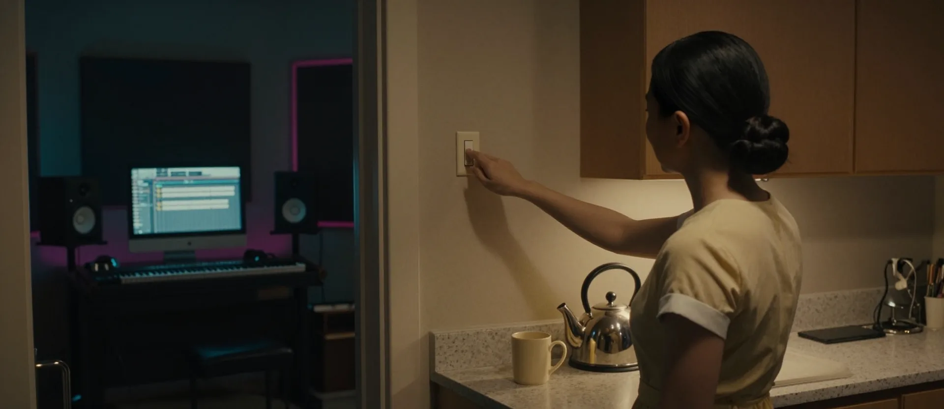 Yuanyue's hand turns off the kitchen light; through the doorway, the studio glows.